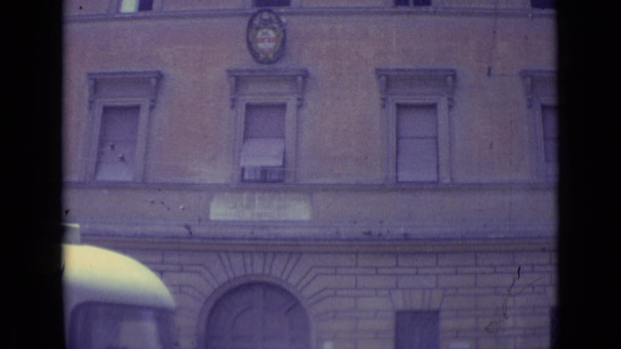1962 Vatican City street detail showing a masonry facade with shuttered windows and the top of a bus or vehicle entering the lower frame.