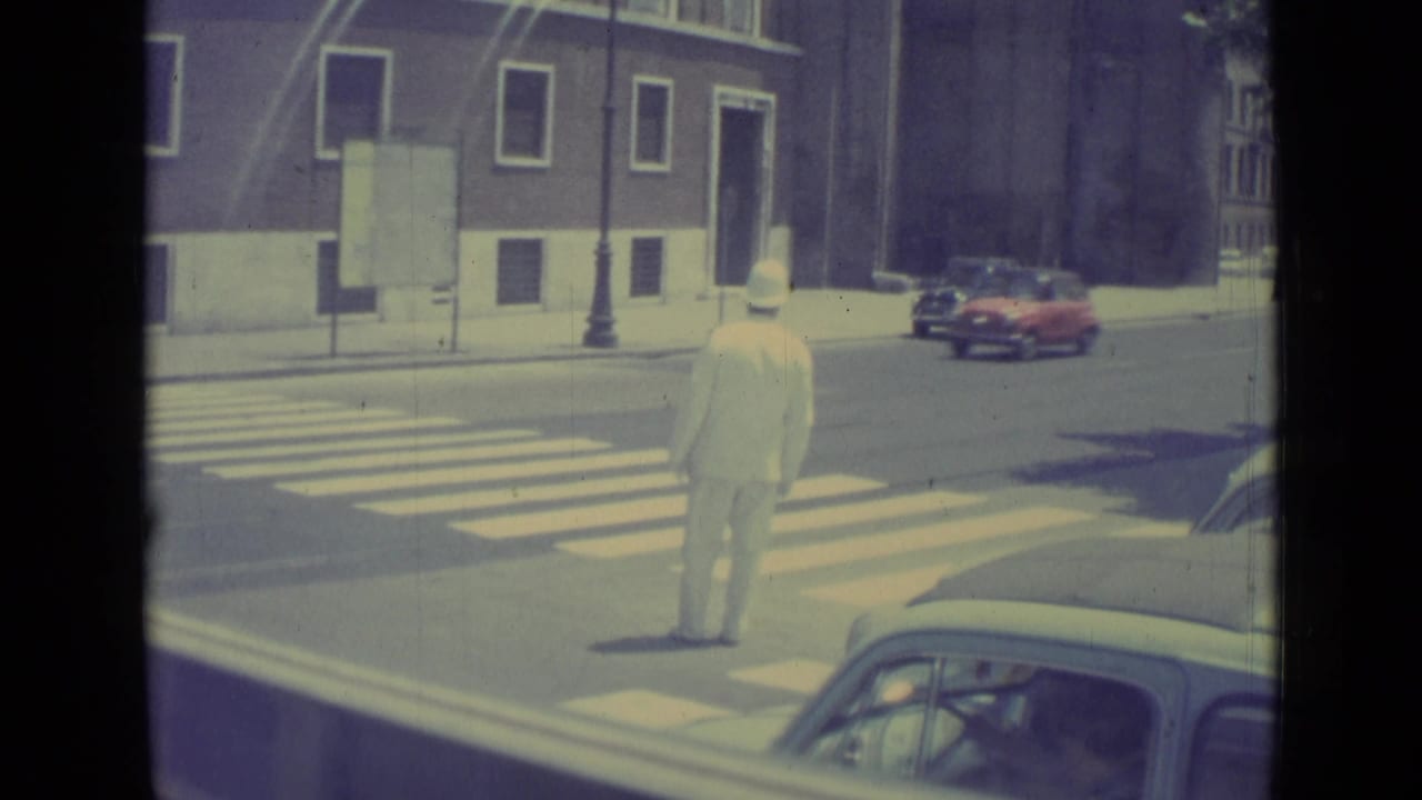 Uniformed traffic officer standing near a crosswalk as vintage cars wait on a city street.