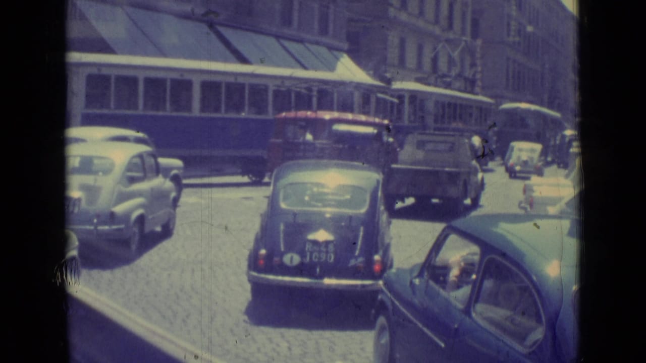 The 1962 Vatican City footage shows cars and a small truck in traffic as a tram passes behind them on a cobblestone street.
