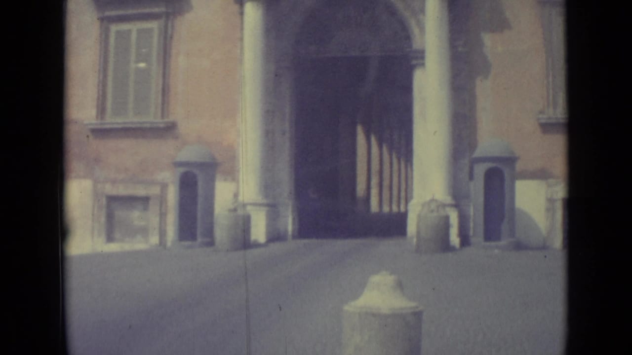 Stone building facade with arched entrance, columns, windows, and street-level masonry.