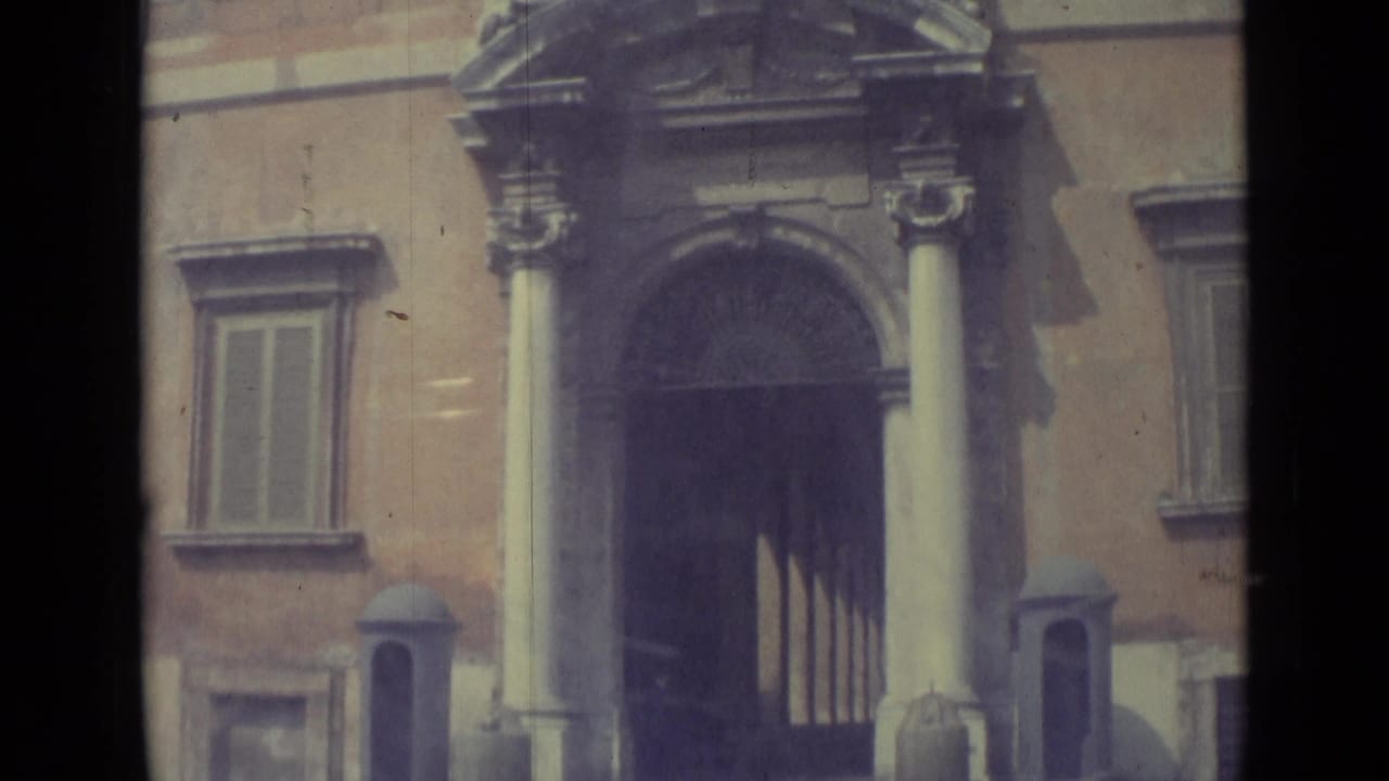 Visitor-shot 1962 Vatican City view of a grand entrance with columns, decorative arch details, windows, and muted 8mm color.