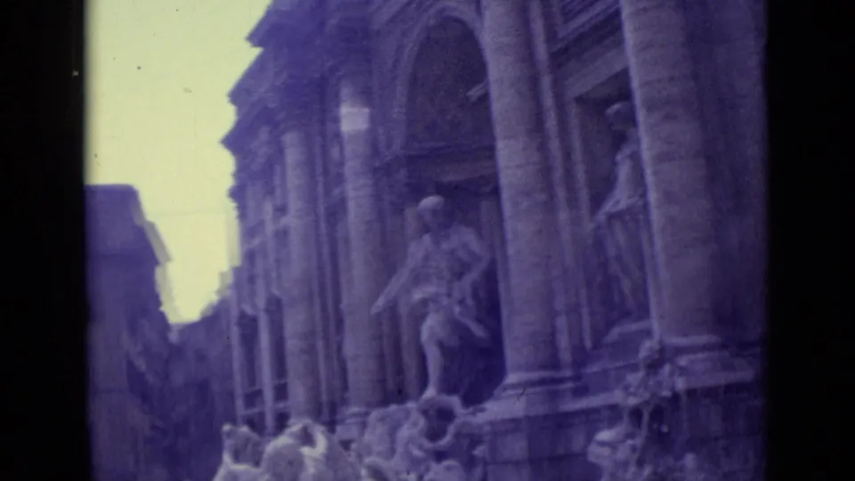 1962 8mm travel frame showing Trevi Fountain statues and columns from a tilted handheld angle.