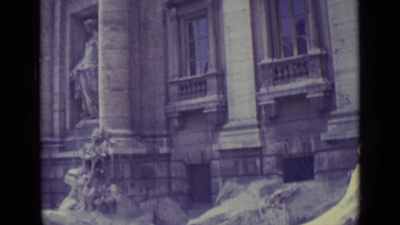 1962 home-movie view of tall columns, windows, and partial Trevi Fountain sculpture with visible grain and color shift.