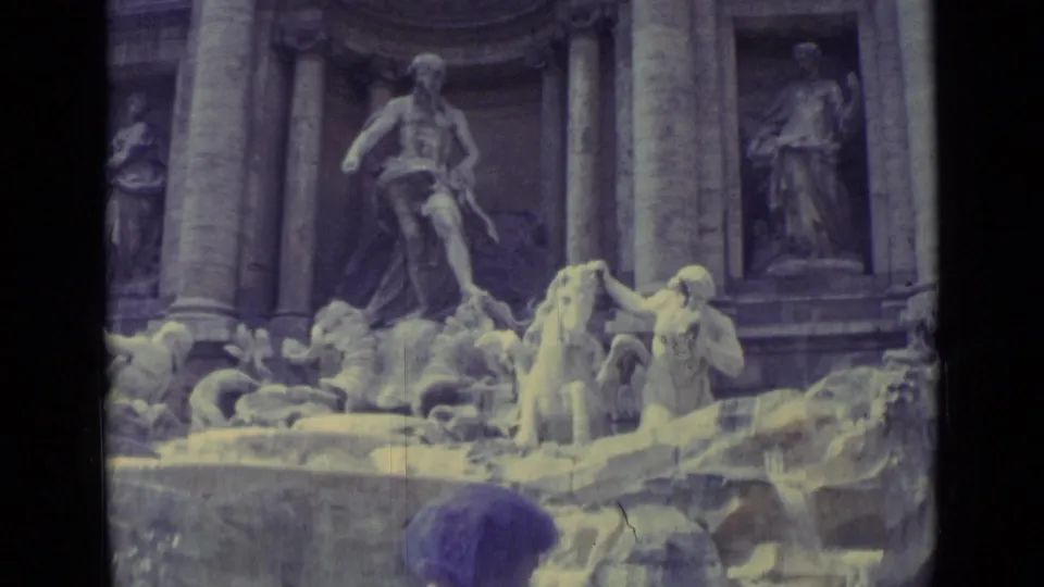 The frame centers on the fountain's sculpted figures and cascading water, with the woman's purple headscarf partly visible below.