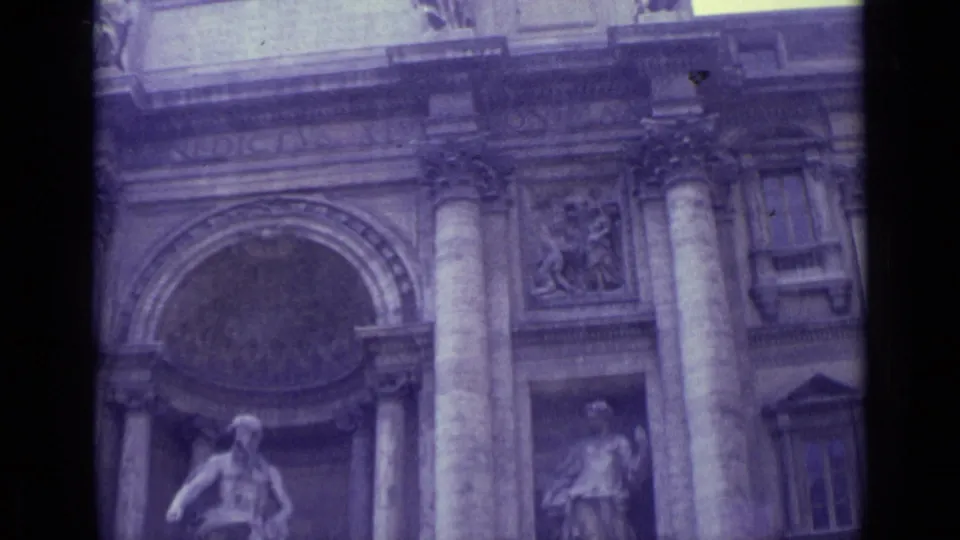 1962 Vatican City home-movie frame showing the lower facade area with an arched recess, column, statue, and carved stonework.