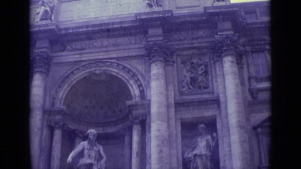 1962 Vatican City frame showing a monumental stone facade with a broad arch, columns, sculpture niche, and visible 8mm film texture.