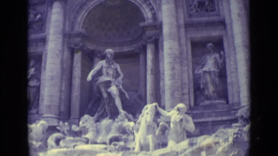 1962 home-movie frame showing the Trevi Fountain's sculptural group, tall facade columns, basin figures, and bright water highlights.