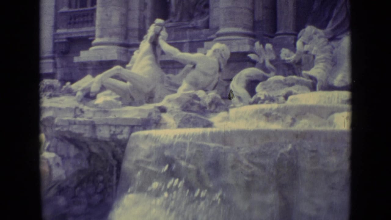 Stone fountain with mythological figures, horses, columns, and water spillover.