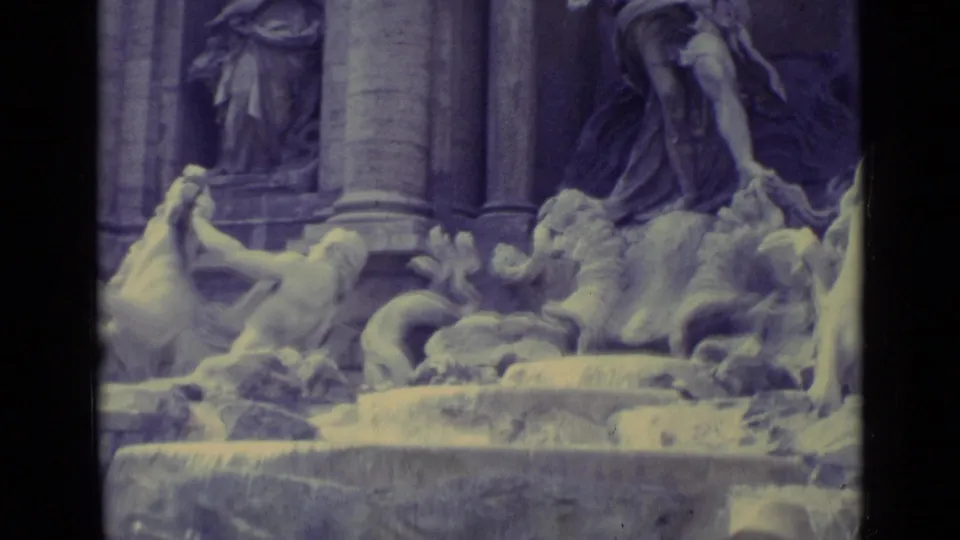 1962 home-movie frame centered on fountain statuary, including a large draped figure, horse form, columns, and flowing water.