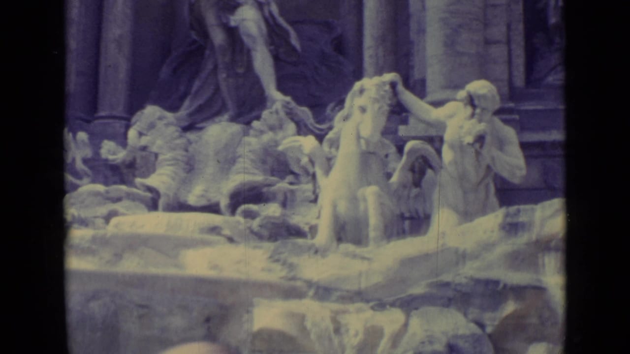 Stone fountain with sculpted figures and horse forms in a faded 8mm frame.