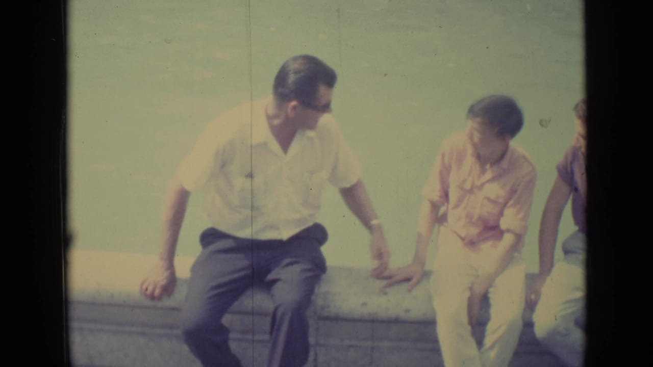 Vatican City 8mm travel frame showing two seated male visitors in conversation near a fountain, with a partial figure at right.