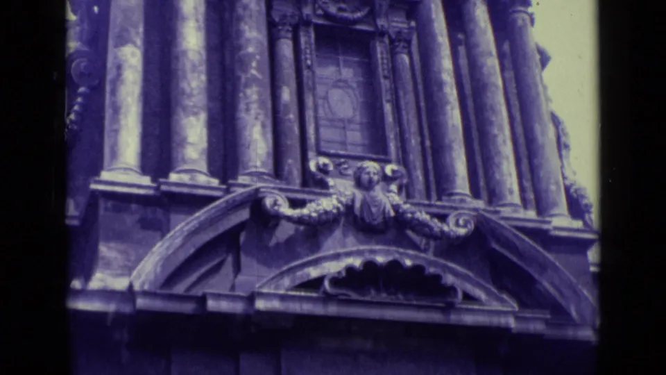 Purple-tinted 8mm view of ornate Vatican City architectural details, including columns, carved figures, and arched stonework.