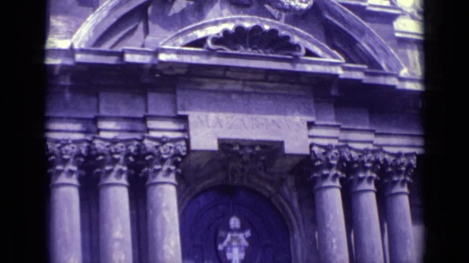 Vatican City architectural facade in 8mm footage, with repeated arches, column capitals, and a shield-like emblem on the doorway.