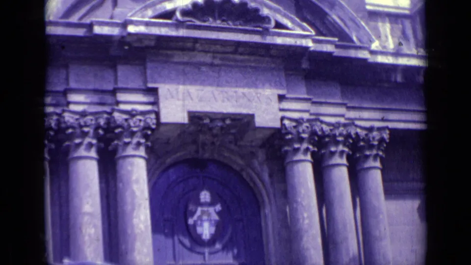 Handheld 8mm view of the same Vatican City institutional entrance, emphasizing columns, carved stonework, and the central doorway emblem.