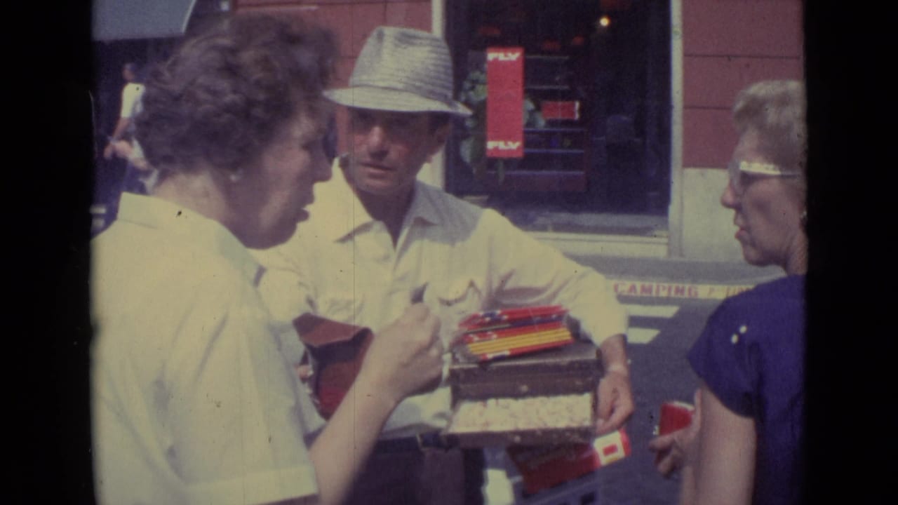 A 1962 Vatican City sidewalk sales moment shows a woman inspecting a small item as the vendor presents goods from a portable box.