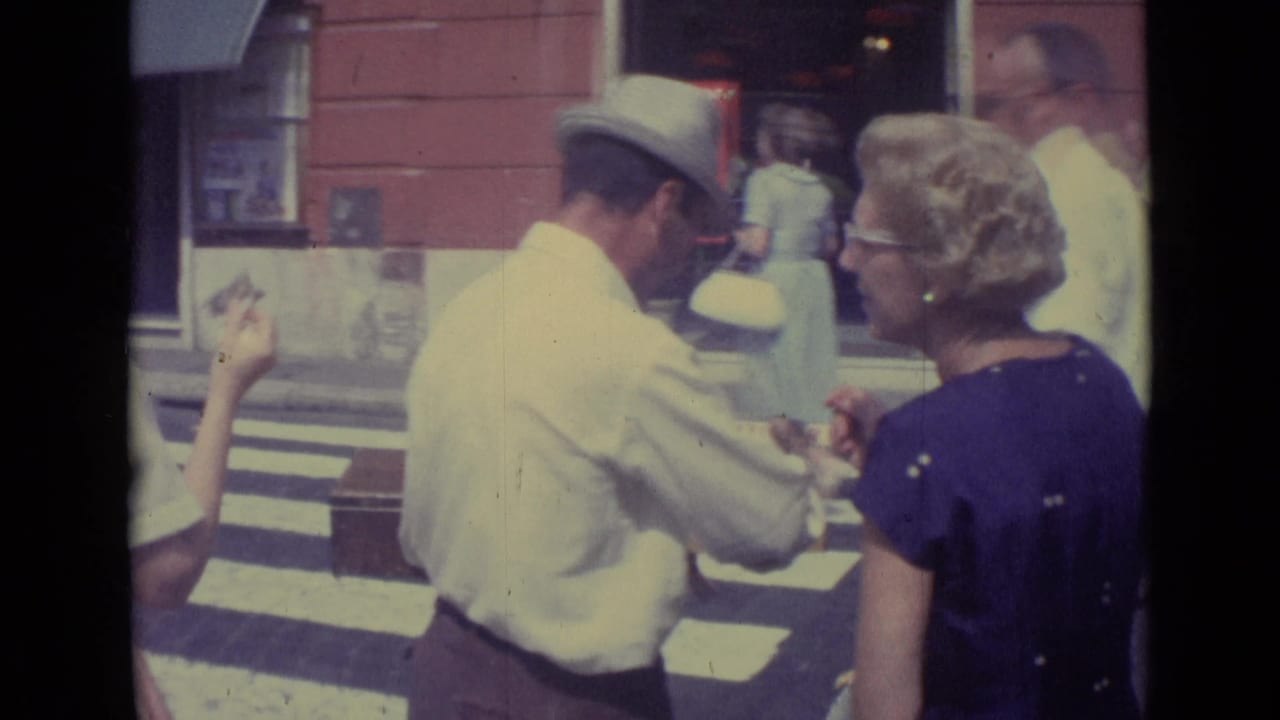 Vendor in a straw hat interacts with a woman in a purple dress near a storefront.