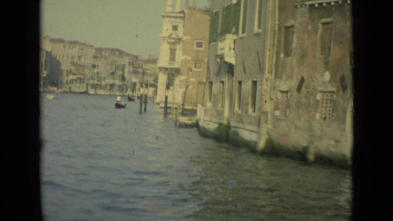 Venetian canal with building facades on the right and a small boat in the distance.