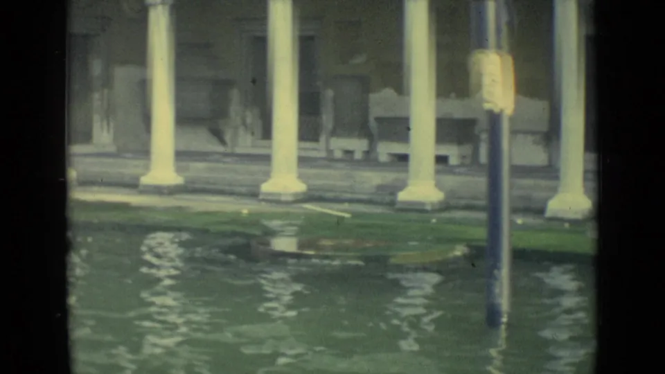 1962 Venice canal-side view with high water, white columns, a dark doorway, benches, and a lamppost rising from the floodwater.