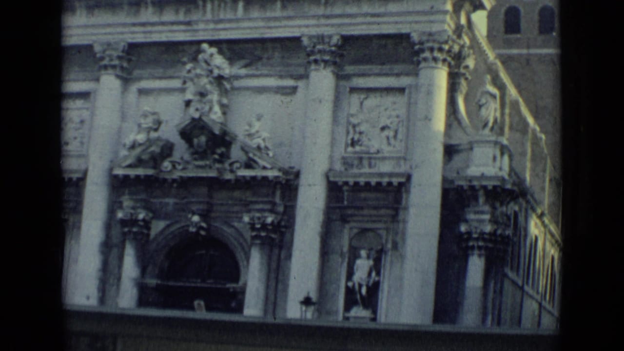 Venice church exterior in 1962 with carved stone ornament, columns, statues, and a dark arched doorway seen from a traveler viewpoint.