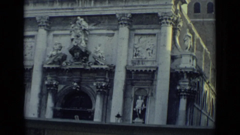 Venice church exterior in 1962 with carved stone ornament, columns, statues, and a dark arched doorway seen from a traveler viewpoint.