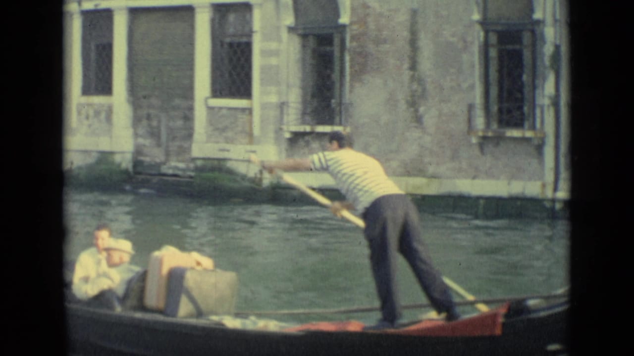 A gondolier steers passengers through a Venice canal, with old plaster walls and shuttered windows behind them.