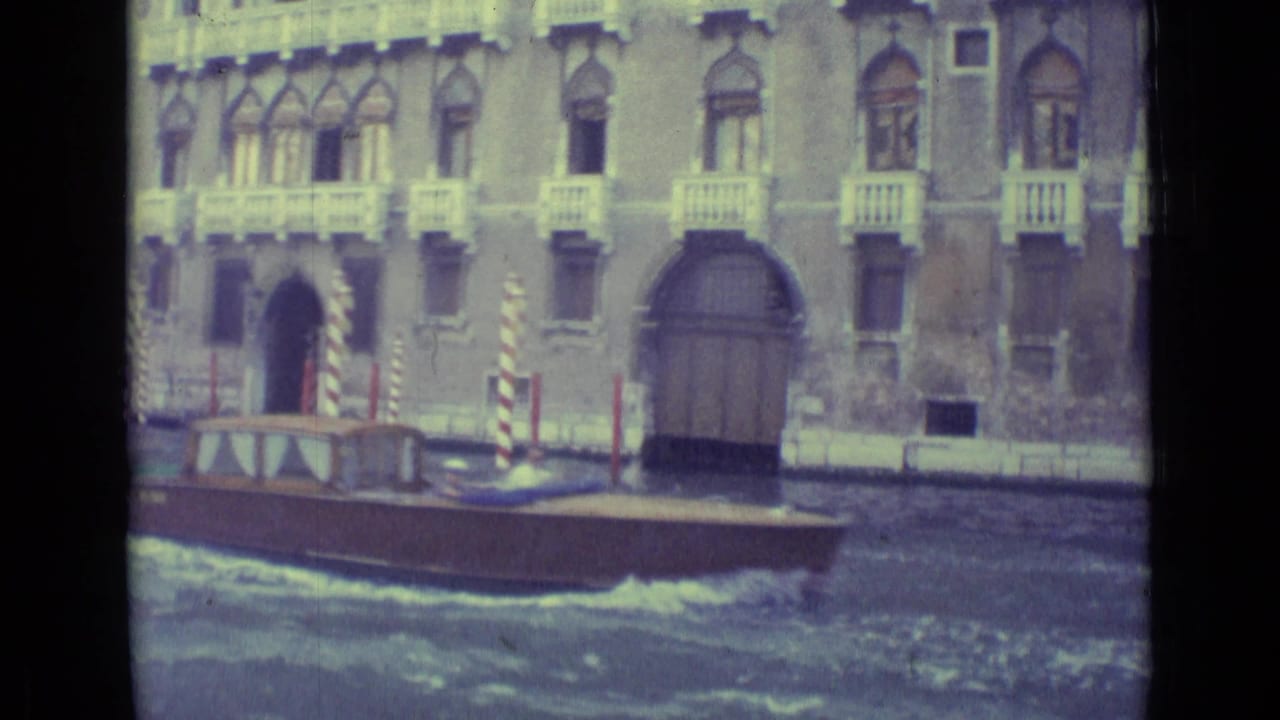 Wooden boat passing a Venetian palazzo facade along a canal.