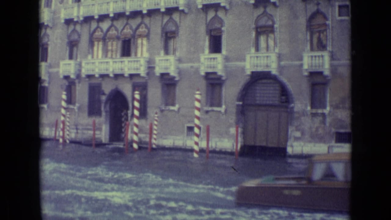 Canal-side building with striped poles and part of a boat at the edge of frame.