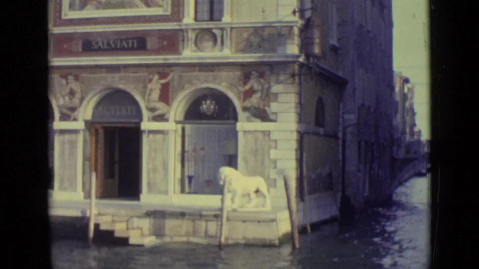 1962 Venice 8mm frame of the SALVIATI canal entrance with arched doors, water steps, and a white lion statue near the canal.