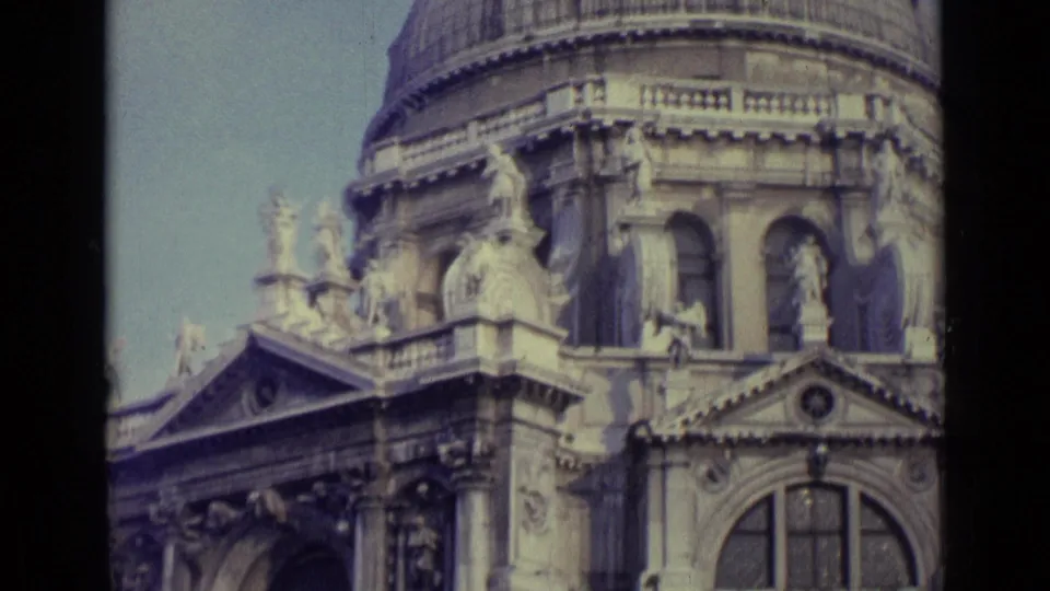 1962 Venice 8mm frame of a historic domed building with statues, pedimented roofline, arched doorway, and classical stone detailing.