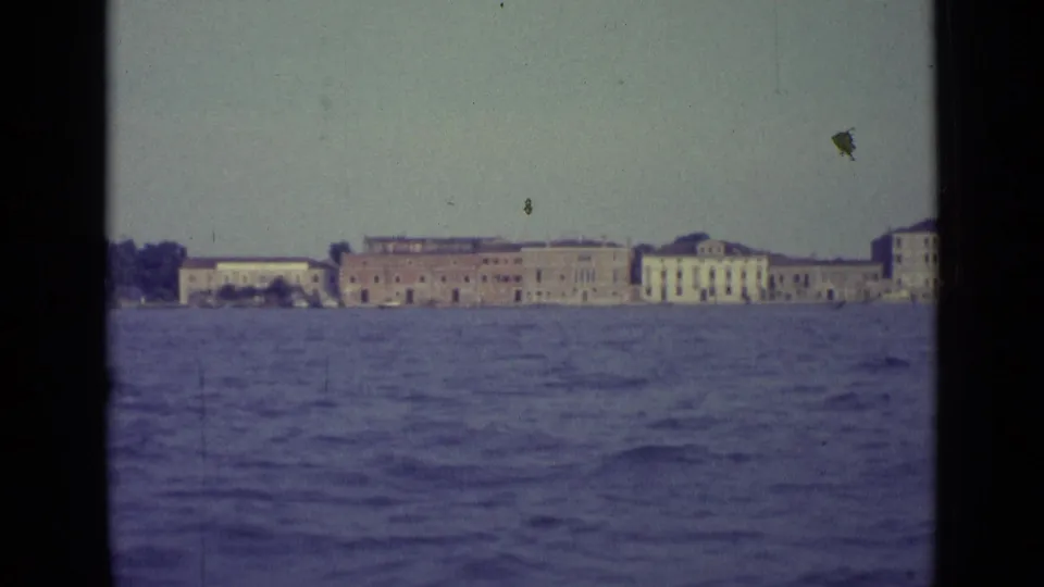 1962 Venice 8mm frame showing low historic waterfront buildings across the water as the pan continues.