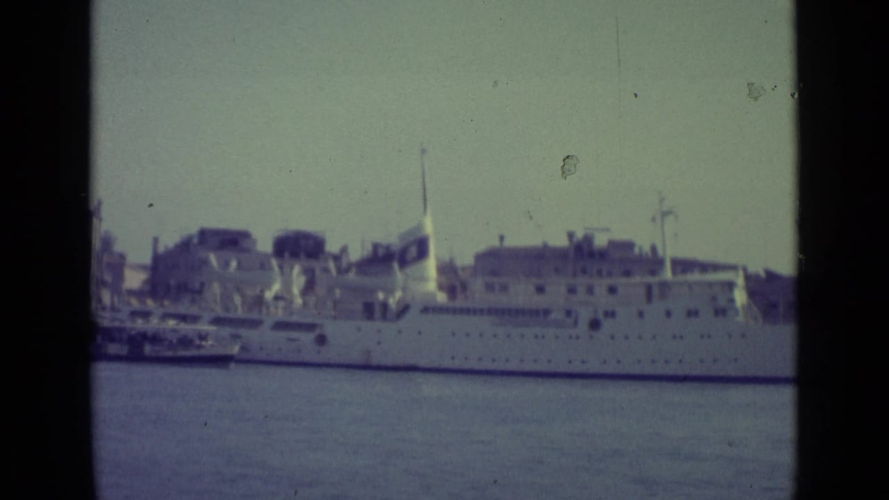 Large white ship docked along a Venice canal with waterfront buildings behind it.