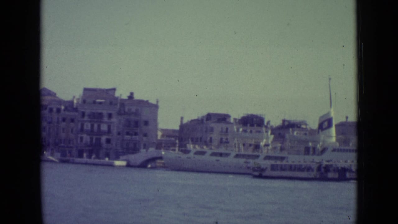 Waterfront buildings and boats seen across a canal under pale daylight.
