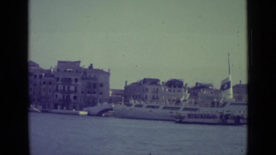 1962 8mm view of Venice waterfront buildings and boats across the Grand Canal, framed from a distance.