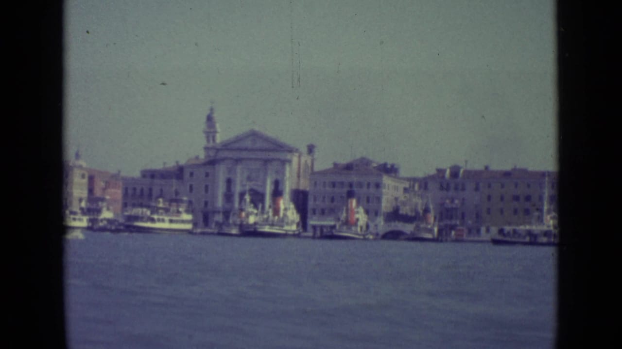 Venice waterfront with lagoon water, boats, and a church facade with bell tower.