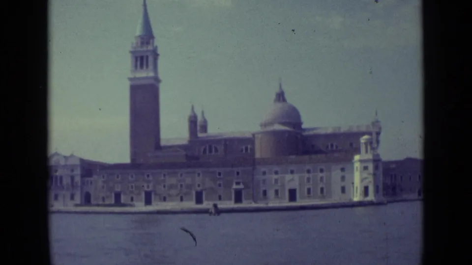 1962 Venice home-movie view of San Giorgio Maggiore, showing the bell tower, dome, waterfront facade, and lagoon foreground.
