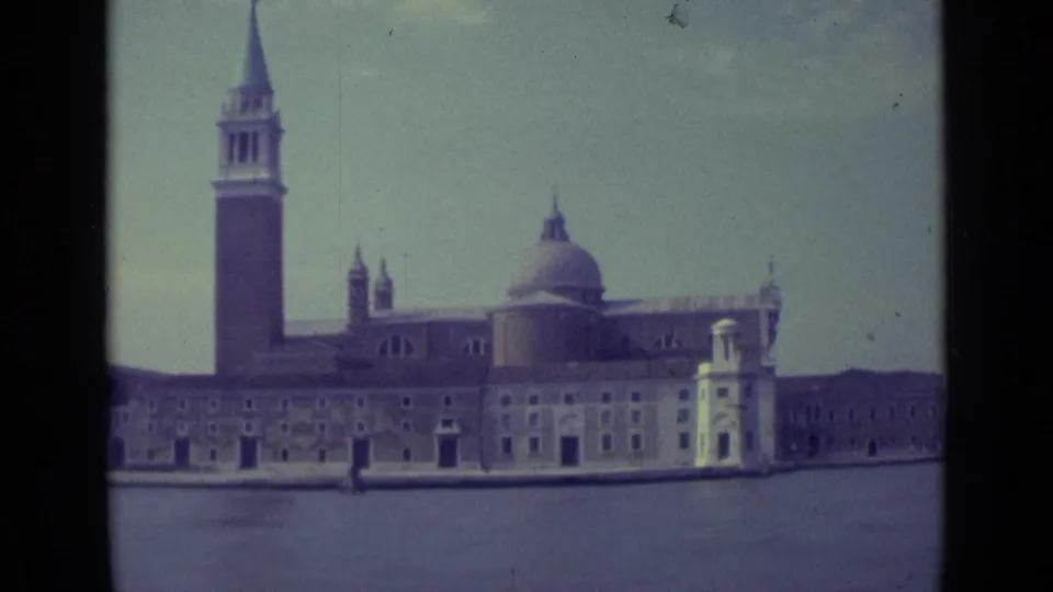 1962 Venice frame holding on San Giorgio Maggiore across the canal, with tower, dome, facade, water, sky, and 8mm frame edge.