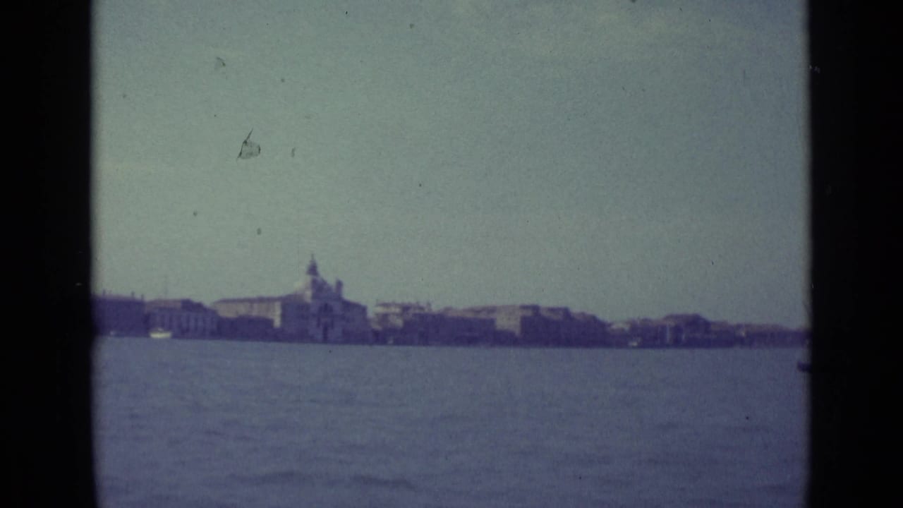 Distant Venice shoreline across open water with a domed church under a pale sky.
