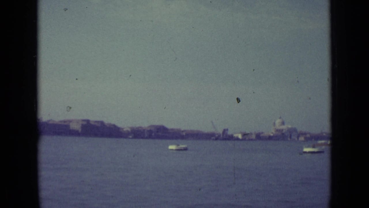 Wide water view toward a distant shoreline with a small boat and domed building visible.