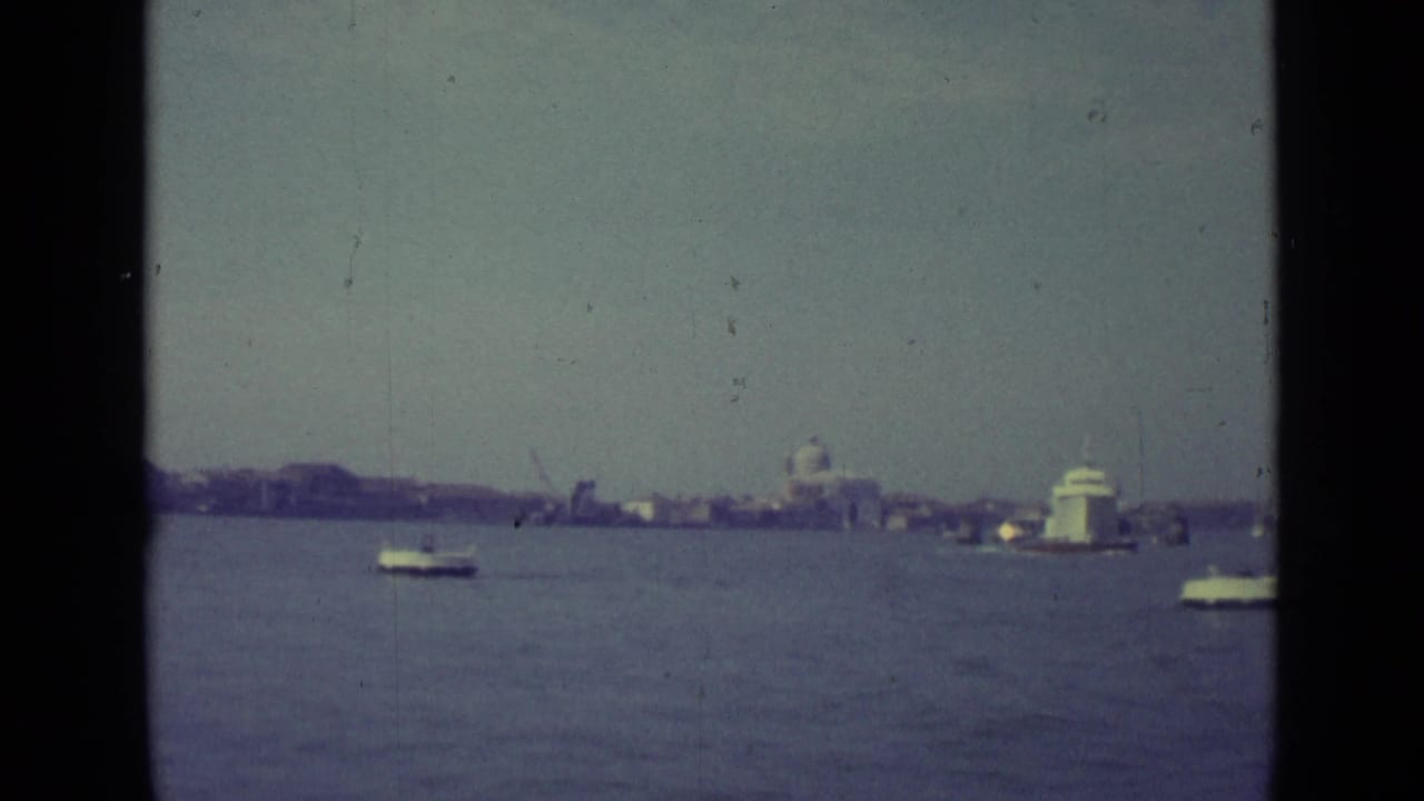 Open water with boats and a distant Venice skyline framed by 8mm gate edges.