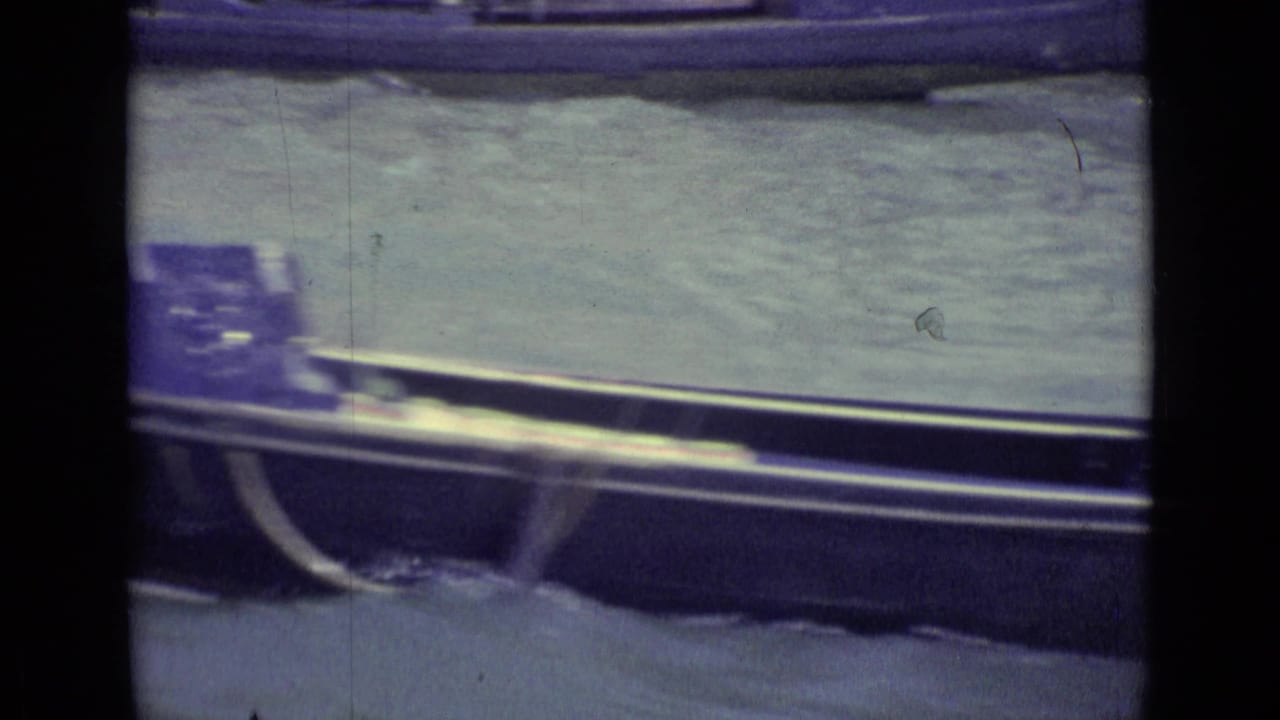 Gondola moving along canal water with another boat edge in the background.