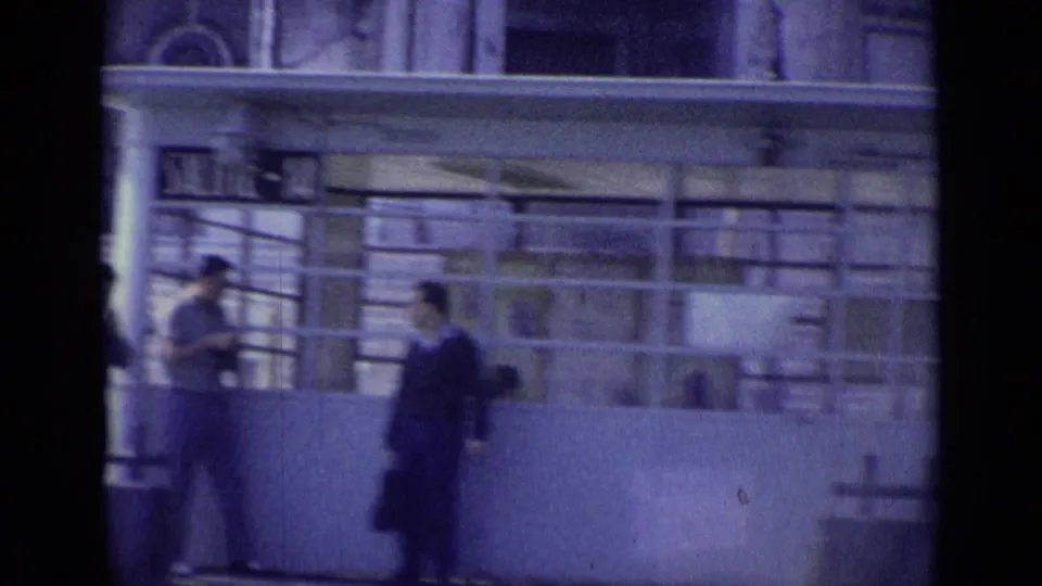 1962 Venice 8mm frame showing men near railings and a public building entrance after the camera pans from the steps.