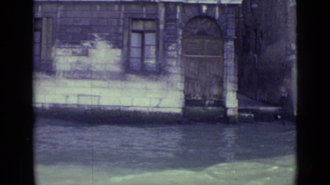 Stone canal facade with arched door, window openings and water below.