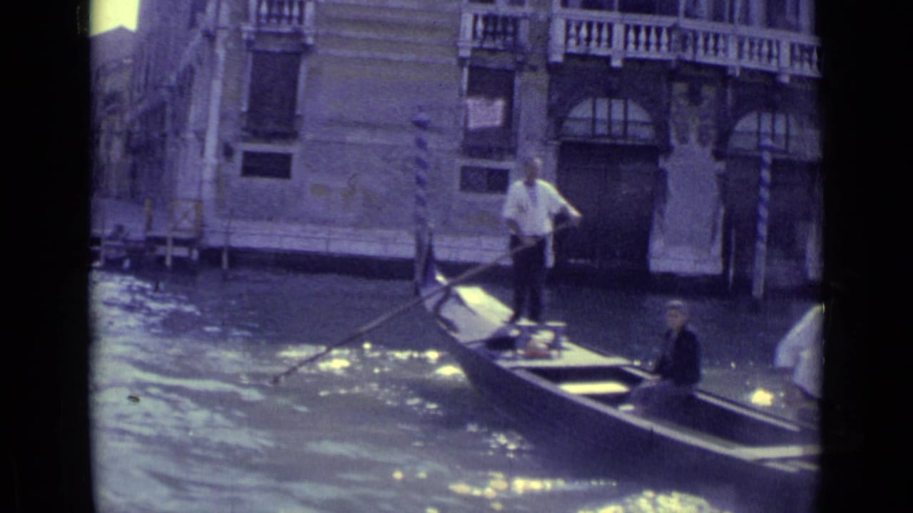 Gondola with standing gondolier and seated passenger beside a Venetian canal facade.