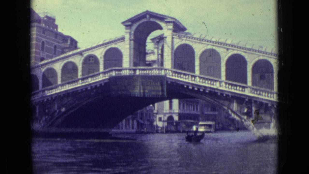 Rialto Bridge over a Venice canal with a gondola and waterfront buildings.