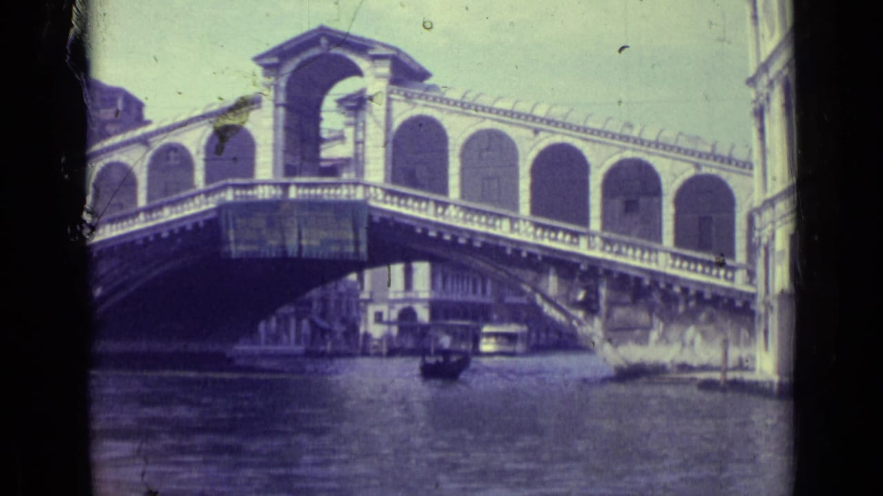 Rialto Bridge seen from the canal with a small boat passing underneath.