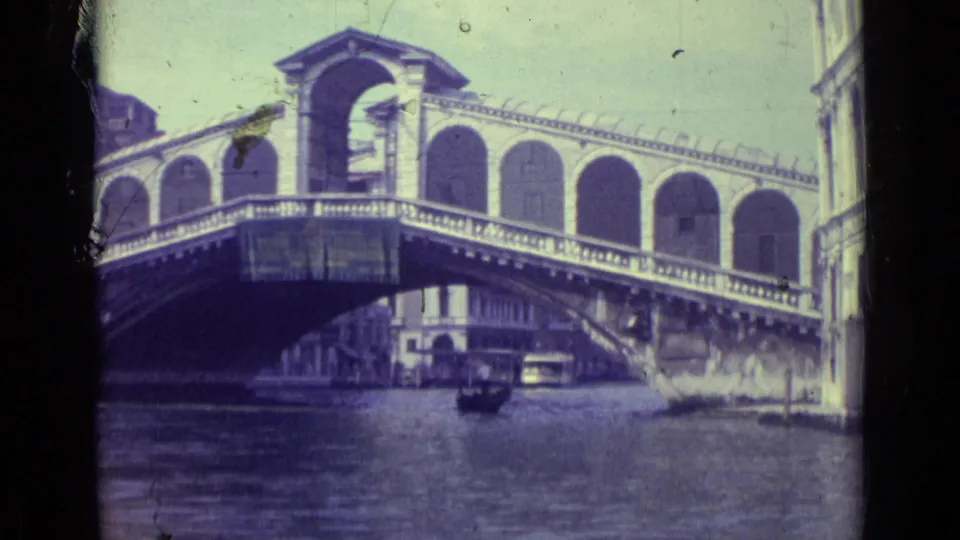1962 Venice canal view of the Rialto Bridge, showing its covered arches and a small boat beneath the span.