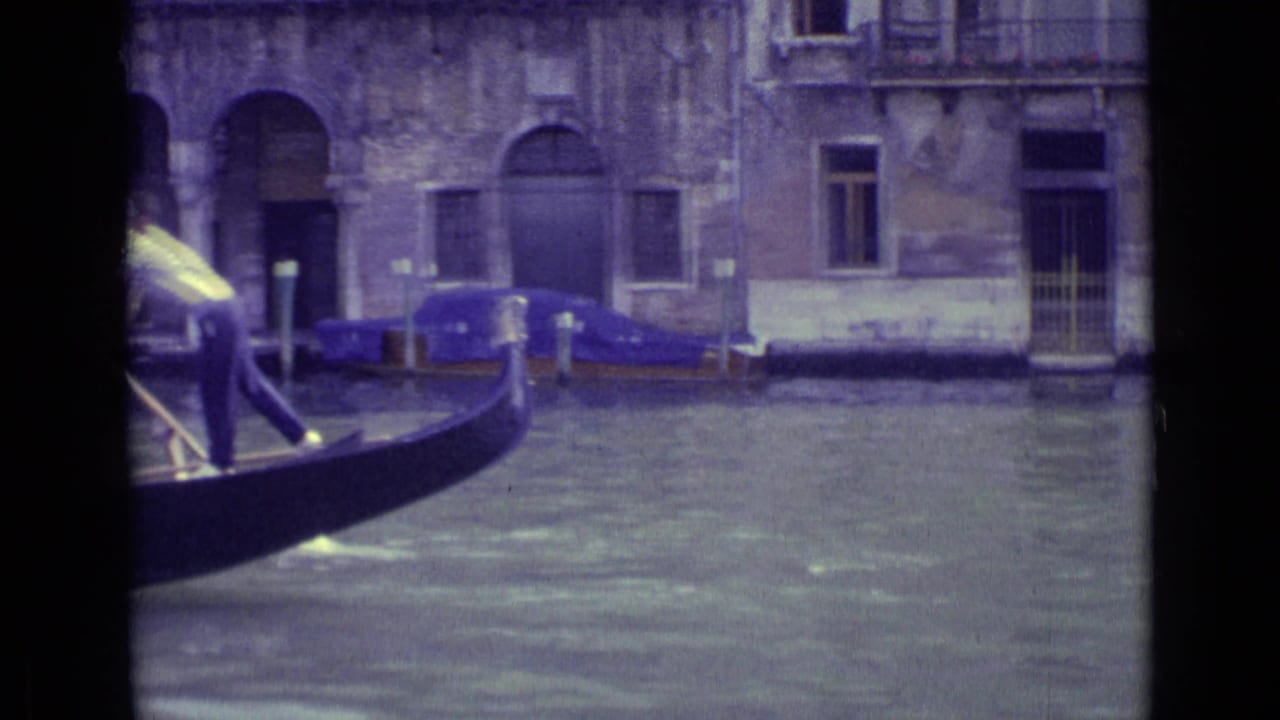 Gondola passes on a Venice canal with a gondolier partly visible and old buildings behind.