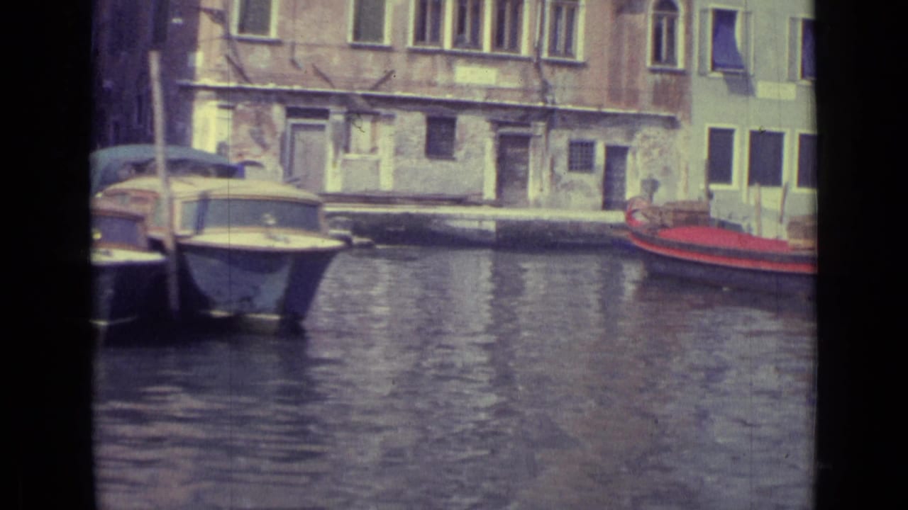 Small boats moored along a Venice canal beside weathered buildings.