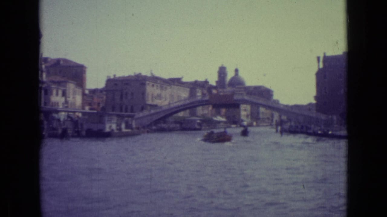 Wide canal view with Rialto Bridge, boats, and historic waterfront buildings.