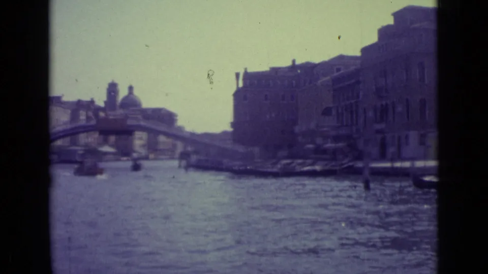Final 1962 Venice frame shows the Rialto Bridge crossing the Grand Canal, with boats, shaded facades, and distant figures near the water.